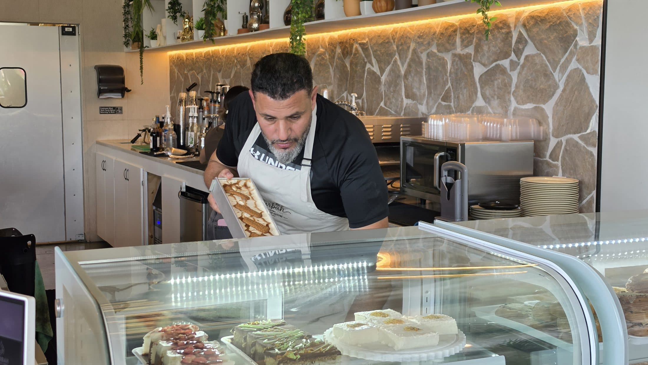 A fresh tray going into the dessert case at Qurbah House of Coffee